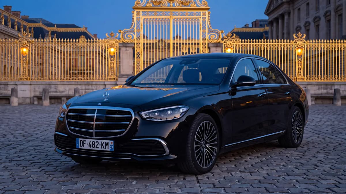 Mercedes S-Class in front of the golden Royal Gate of the Palace of Versailles at blue hour